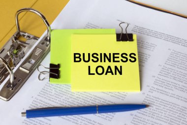 Belgeler ve mavi kalemle dolu bir klasörde bulunan sarı bir çıkartma üzerine Text Business Loan yaz. İş konsepti