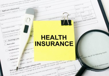 Metin Sağlık Sigortası, büyüteç ve elektronik termometrenin yanındaki sarı etikete yazılır. Tıbbi konsept