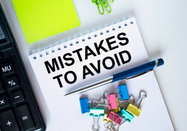 Üzerinde ataç ve kalem olan kısa mesaj hatalarından kaçınmak için bir not defteri. Hesap makinesi ve sarı çıkartmalar. Konsept fotoğraf olarak kullanılabilir