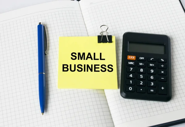 Kalkulator Niebieskim Długopisem Żółtą Naklejką Tekstem Small Business Leży Notatniku — Zdjęcie stockowe