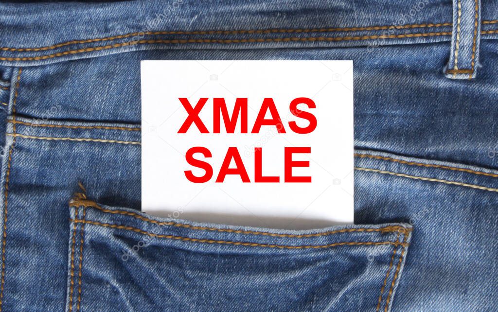Text Xmas Sale on white paper in the pocket of blue denim jeans. Can be use as marketing concept