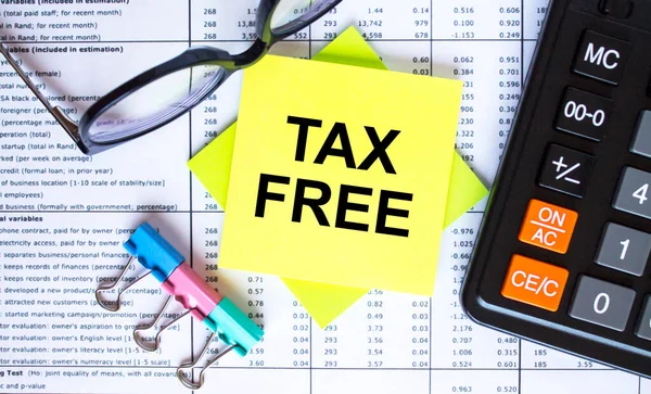 Text Tax Free on yellow stickers with calculator, eyeglasses and paper clips. Business and financial concept
