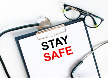 Stetoskop ve gözlüklerle klasörde güvende kal mesajı. Tıbbi konsept fotoğrafı