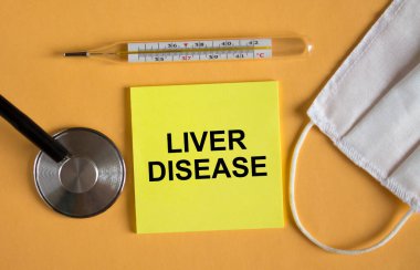 Maske ve termometreyle turuncu arka planda duran karaciğer hastalığı etiketi. Tıbbi konsept