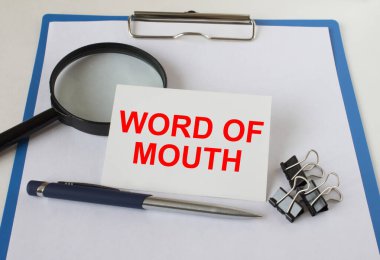 Not Word of Mouth bir not panosunun üzerinde, büyüteç kalem ve ataçlarla. İş konsepti