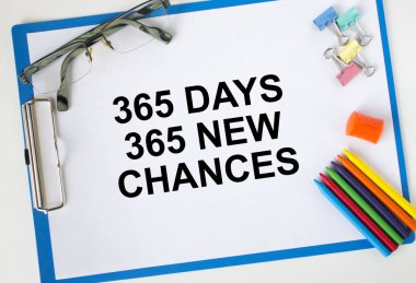 365 gün metin içeren bir pano 365 yeni şans gözlük kağıdı bir kalemciyi ve renkli kalemleri kırpıyor
