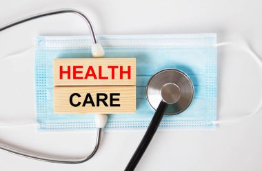 Maskenin üzerinde yazılı tahta bloklar ve steteskop var. Tıbbi konsept