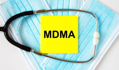 Yellow sticker with text MDMA lying on the masks and stethoscope. Medical concept clipart