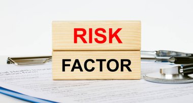 Tahta bloklar, bir not panosu ve stetoskop üzerinde Risk Faktörü yazılı. Tıbbi konsept