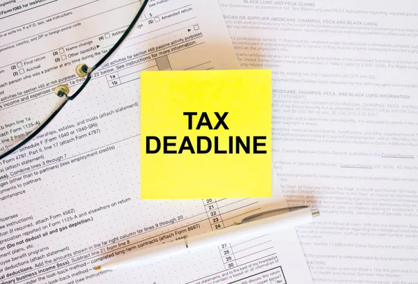 Yellow sticker with text Tax Deadline on financial docs. Financial concept