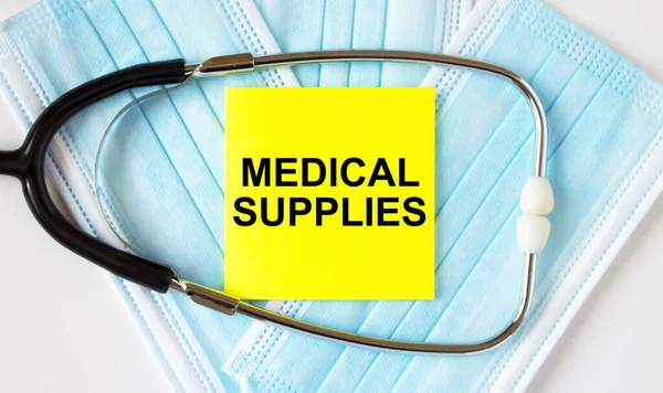 Yellow sticker with text Medical Supplies lying on the masks and stethoscope. Medical concept