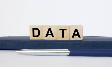 Metin Data tahta küplerin üzerinde, metal mavi bir kalemle Notepad 'in üzerinde yatıyor. İş konsepti fotoğrafı