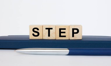 Metin, tahta küplerin üzerinde, metal mavi bir kalemle Notepad 'in üzerinde duruyor. İş konsepti fotoğrafı