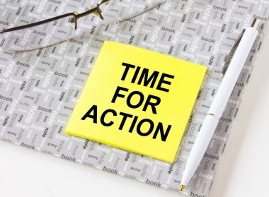 Gözlük ve kalemle bir not defterinin üzerinde duran sarı bir çıkartma üzerinde 