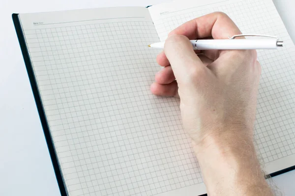 Pen in hand writing on the notebook and reflection isolated on white