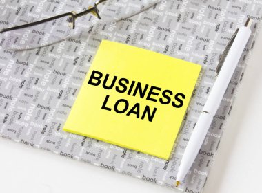 Gözlük ve kalemle birlikte bir not defterinde duran sarı etiketteki İş Kredisi 'ne mesaj at. İş, mali ve pazarlama kavramları için olabilir.