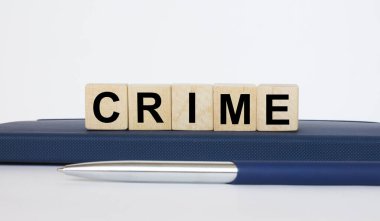 Metin Suçları, tahta küplerin üzerinde, metal mavi kalemle bir not defterinin üzerinde yatıyor. İş konsepti fotoğrafı