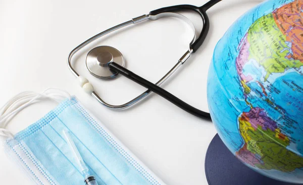 World globe with medical face mask and medical stethoscope. Pandemic concept, Virus, Coronavirus, Covid-19, international emergency, global quarantine