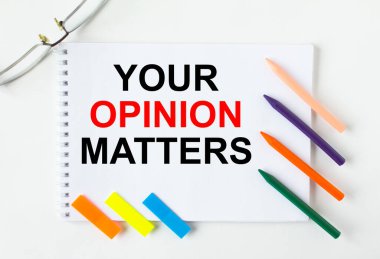 Notepad with text Your Opinion Matters glasses colored pencils and colored stickers. Concept photo