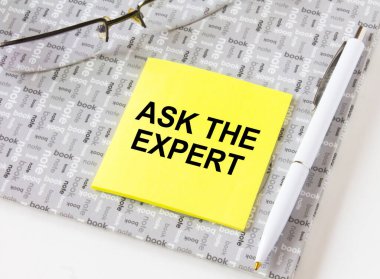 Gözlüklü ve kalemli bir not defterinde duran sarı bir çıkartmayla ilgili 