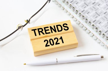 Metin Eğilimleri 2021 tahta bloklarda gözlük ve kalemle not defterinin yanında yatıyor. İş, mali ve pazarlama kavramları için olabilir.