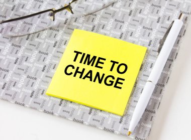 Gözlük ve kalemle bir not defterinde duran sarı etiketi değiştirme zamanı. İş, mali ve pazarlama kavramları için olabilir.