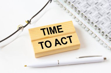 Gözlük ve kalemle not defterinin yanında duran tahta bloklarda harekete geçme zamanı. İş, mali ve pazarlama kavramları için olabilir.