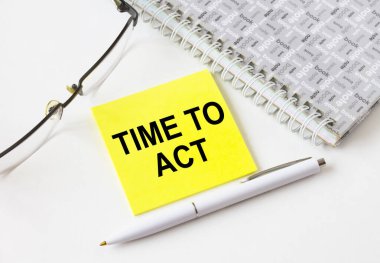 Gözlük ve kalemle not defterinin yanında duran sarı bir çıkartmayla harekete geçme zamanı. İş, mali ve pazarlama kavramları için olabilir.