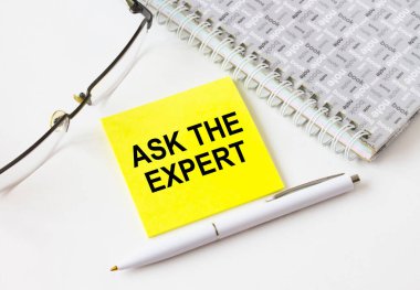 Gözlük ve kalemle not defterinin yanında duran sarı bir çıkartma üzerinde 