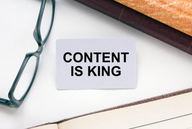 Text Content is King kartvizitte gözlüklü ve metin belgeli not defterinin yanında yatıyor. İş konsepti