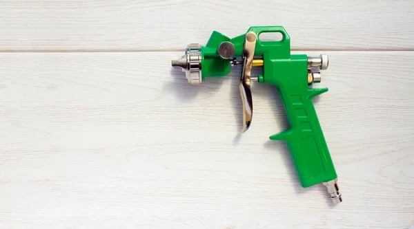Green air compressor gun. Isolated on a wooden background. Industrial concept