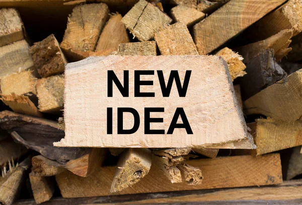 Wall firewood. Background of dry chopped firewood logs in a pile and plate with text New Idea. Concept photo