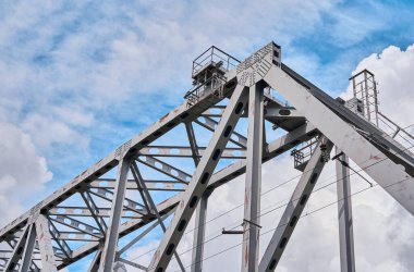 Bulutlu bir gökyüzüne karşı nehir üzerinde demir tren köprüsü. Yakın plan.