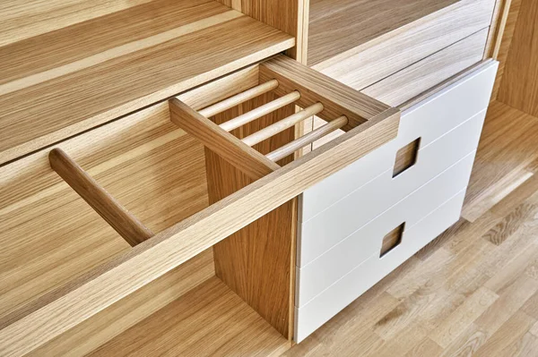 Internal details of the wooden wardrobe with slide out rack for coathangers. Oak veneered plywood cabinets with light gray painted cabinet doors. Detail of modern furniture