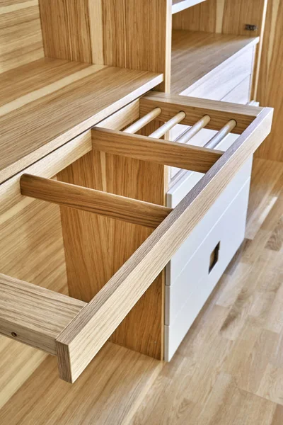 Internal details of the wooden wardrobe with slide out rack for coathangers. Oak veneered plywood cabinets with light gray painted cabinet doors. Detail of modern furniture