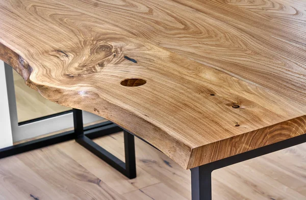 Live edge elm gaming desk countertop with metal base in a modern home office. Details close-up