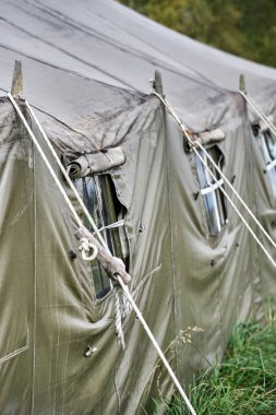 Ormandaki çimlerin üzerinde pencereleri ve sobası olan büyük bir askeri çadır. Çadır penceresi yakın plan