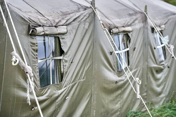 Big military field tent with windows and a stove on the lawn in the forest. Tent window close-up