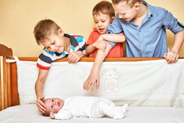 Mutlu abiler dikkatli bakın ve nazikçe dokunun. Yumuşak, beyaz vücutlu, ahşap karyolada uzanan küçük kardeş.