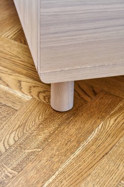 Çağdaş sandık, parlak meşe ağacından yapılmış, parmak çekme çekmeceleri ahşap blok parke zemininde duruyor.