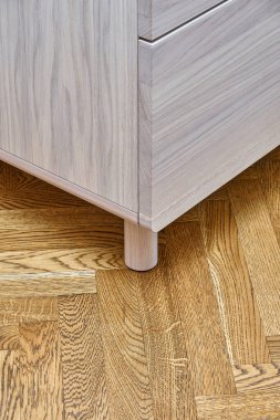 Çağdaş sandık, parlak meşe ağacından yapılmış, parmak çekme çekmeceleri ahşap blok parke zemininde duruyor.