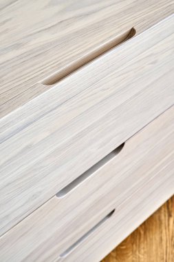 Çağdaş çekmeceler, beyazlatılmış sert meşe ağacından yapılmış, parmak çekme çekmeceleri, ışık odasında yerde duruyor.