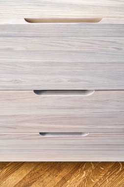 Çağdaş çekmeceler, beyazlatılmış sert meşe ağacından yapılmış, parmak çekme çekmeceleri, ışık odasında yerde duruyor.