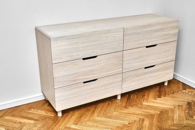 Çamaşır beyazlatılmış sert meşe ağacından yapılmış zarif çekmeceler parmak çekme çekmeceleri aydınlatma odasındaki ahşap parke zemininde duruyor.