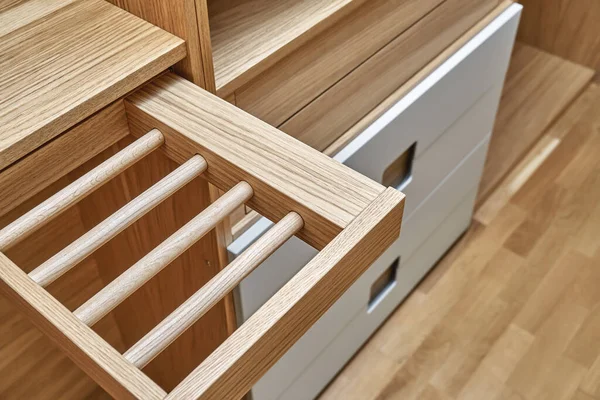 Internal details of the wooden wardrobe with slide out rack for coathangers. Oak veneered plywood cabinets with light gray painted cabinet doors. Detail of modern furniture