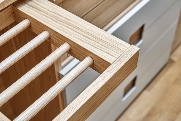 Internal details of the wooden wardrobe with slide out rack for coathangers. Oak veneered plywood cabinets with light gray painted cabinet doors. Detail of modern furniture