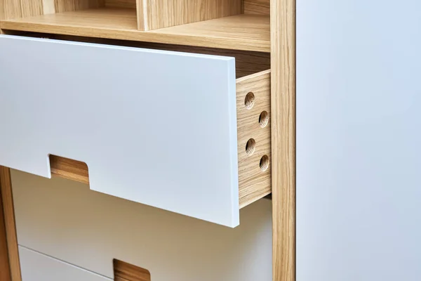 Detail of the wardrobe close-up. Modern wardrobe with opened wooden drawers. Wooden wardrobe with flat finger pull wardrobe doors. Oak veneered plywood cabinets with light gray painted cabinet doors