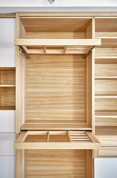 Internal details of the wooden wardrobe with slide out rack for coathangers. Oak veneered plywood cabinets with light gray painted cabinet doors. Detail of modern furniture