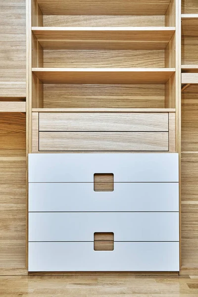 Internal details of the wooden wardrobe. Modern wooden wardrobe with flat finger pull wardrobe doors. Oak veneered plywood cabinets with light gray painted cabinet doors. Modern furniture