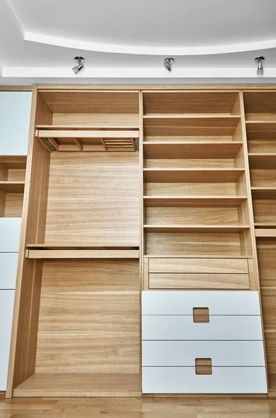 Internal details of the wooden wardrobe. Modern wooden wardrobe with flat finger pull wardrobe doors. Oak veneered plywood cabinets with light gray painted cabinet doors. Modern furniture